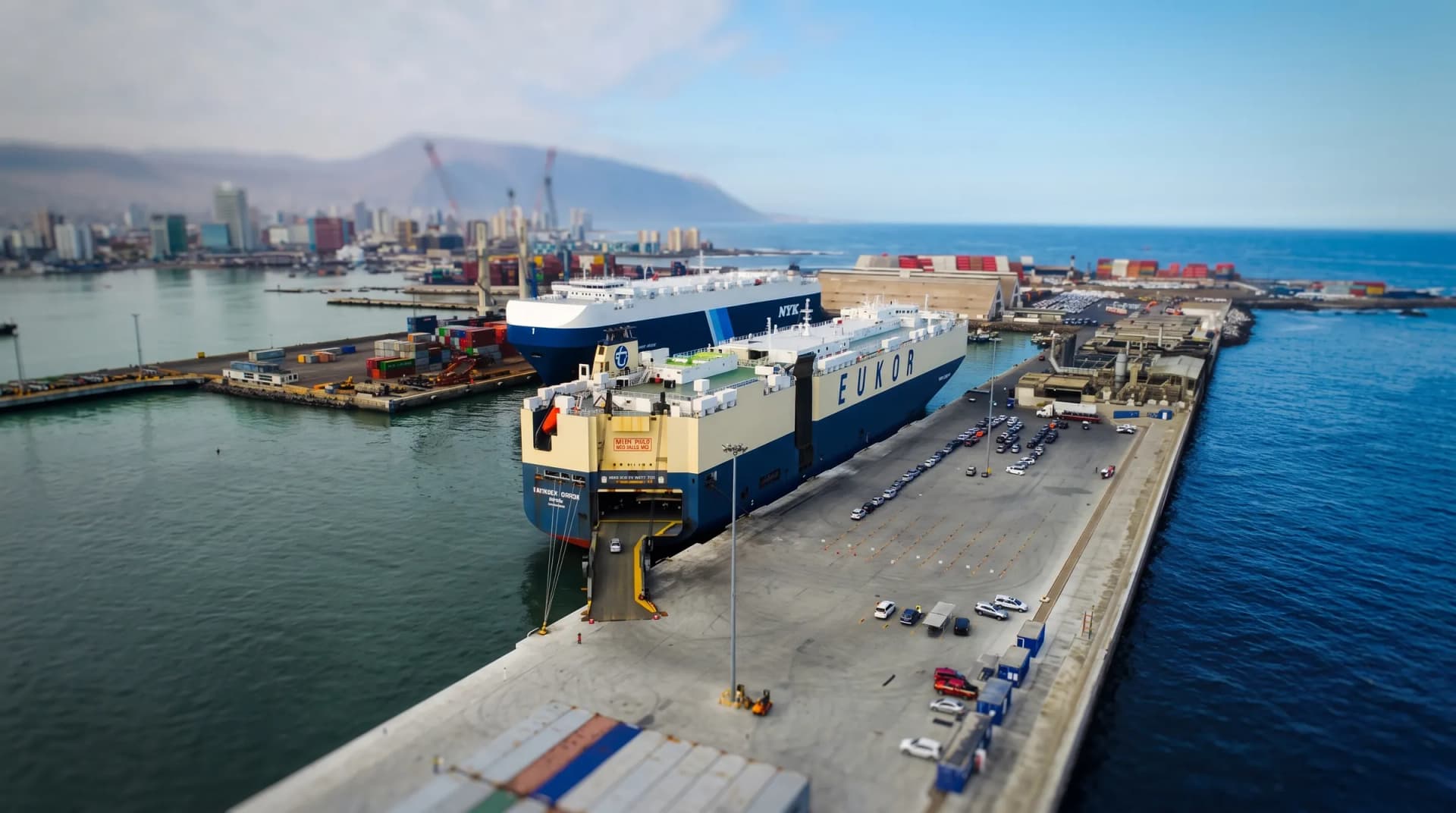 Vista aérea del puerto de Iquique con un buque atracado, patios de contenedores y la ciudad al fondo